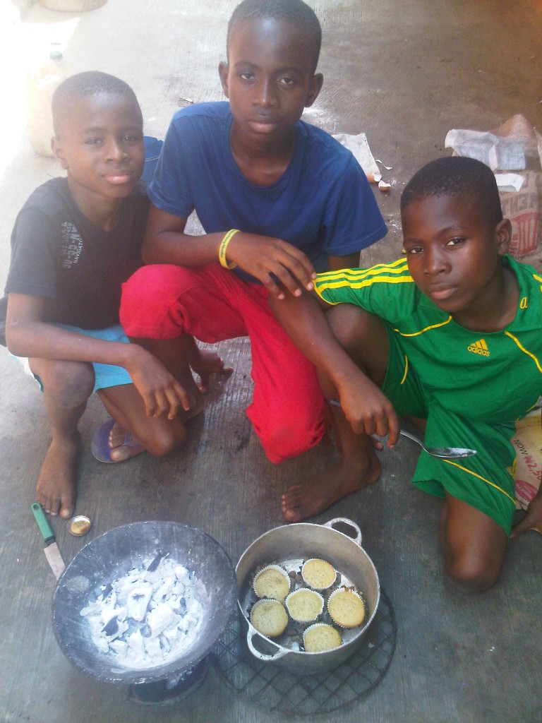 Photo: Wed. Dec. 11, 2013 - My 10, 14, and 12 year old sons, and the 50% pineapple peel cakes they baked WITHOUT an oven. All they used was the charcoal stove, and a heavy metal pot I brought ALL the way from Cotonou